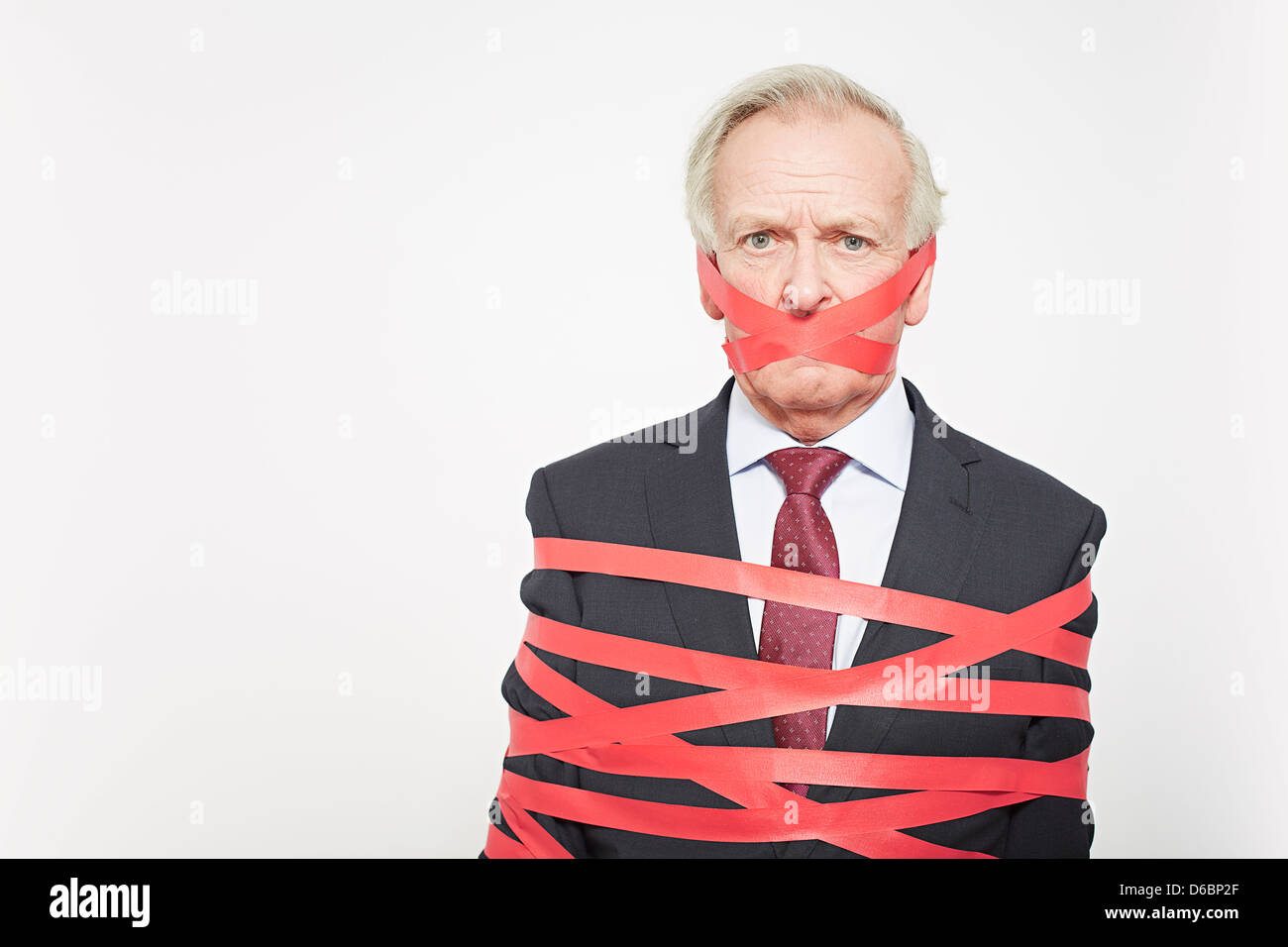 Businessman wrapped in red tape Stock Photo