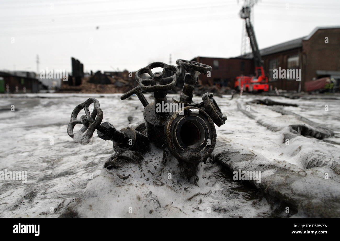 A hose connector lies on the ground covered with melted bitumen and