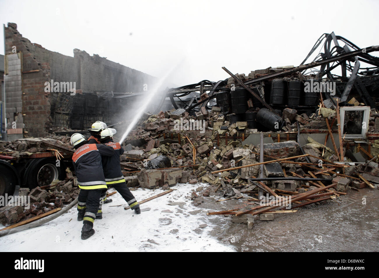 Firefighters extinguishes the remains of a burnt-out warehouse in Hamburg, Germany, 03 January 2012. According to the fire brigade, the largest fire in years broke out in an industrial park in Hamburg in the afternoon of 02 January 2012. The fire-fighting operations continued until the early morning. Photo: DANIEL BOCKWOLDT Stock Photo