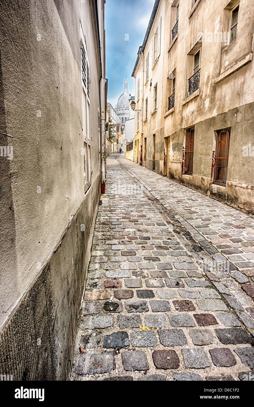 Narrow street in Montmartre and Basilica of Sacred Heart far away Stock Photo