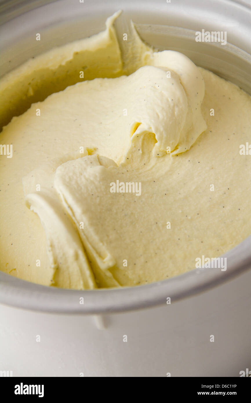 Creamy, homemade traditional vanilla ice cream in ice cream maker freezer bowl, swirled and soft. Stock Photo