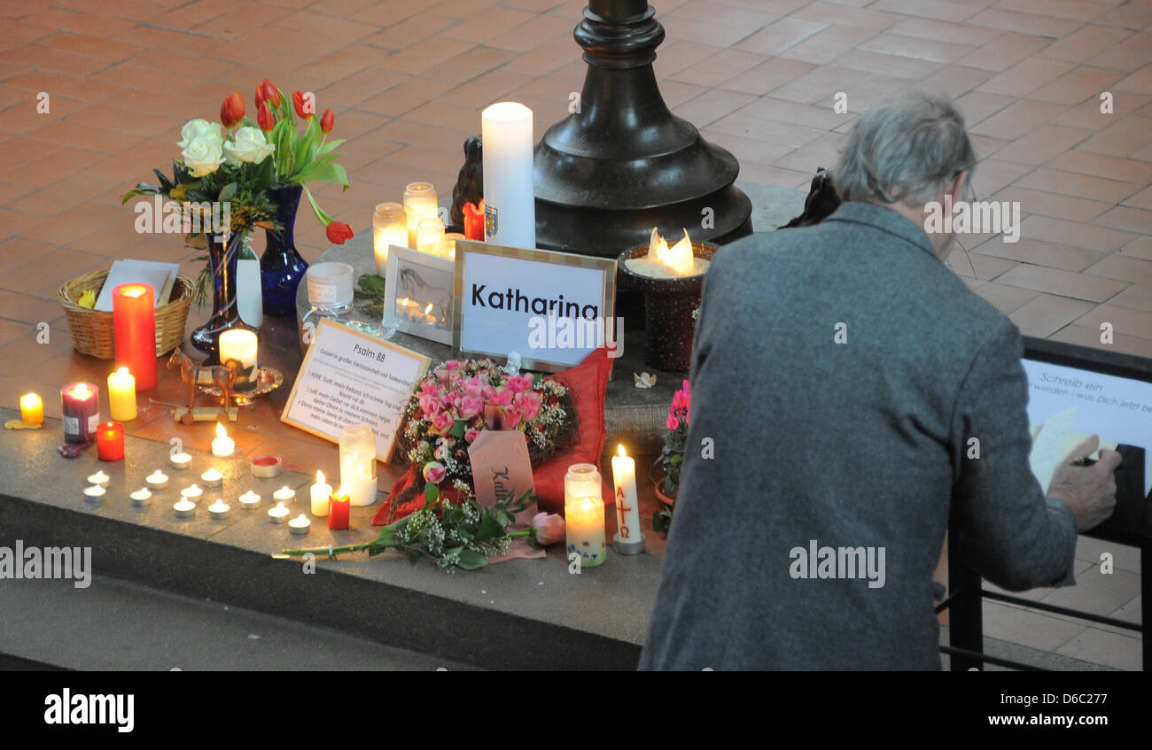 A man signs the book of condolences next to lit up candles and flowers commemorating ten year old Katharina at Saint Jacobi Church in Perleberg, Germany, 10 January 2012. Since 26 December 2011, Katharina had been missing. On Monday afternoon, 26 December 2011, several thousand cubic metres of clay and chalkstone crashed into the sea at Cape Arkona taking by surprise a mother and h Stock Photo
