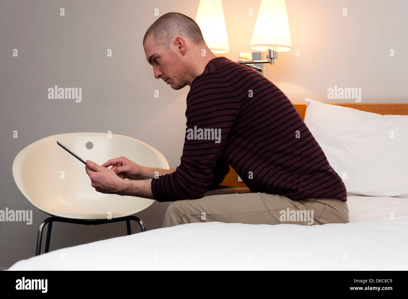 Man using tablet computer in hotel room. Stock Photo