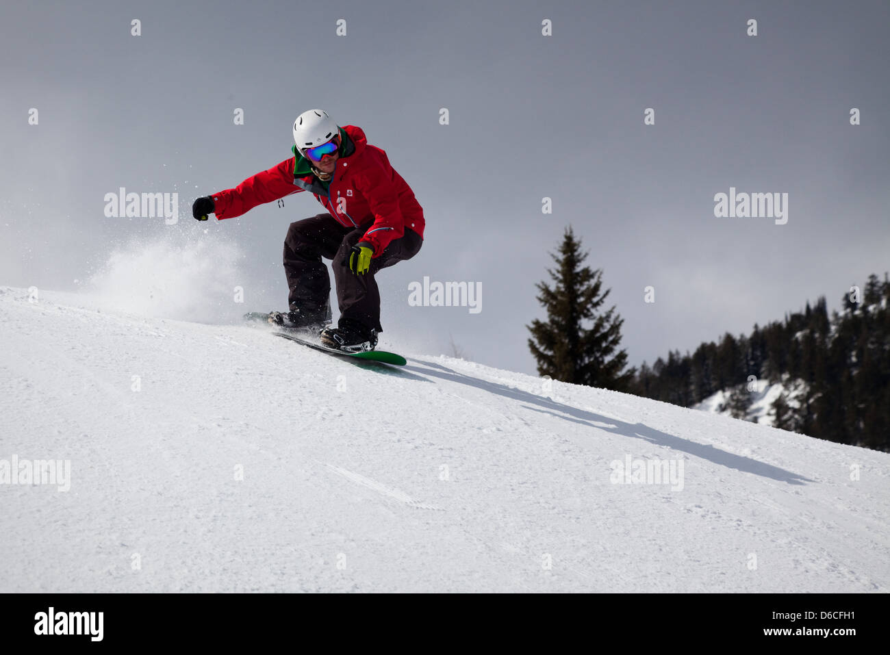 A snowboarder lands after making a jump at Red Mountain resort, Canada Stock Photo
