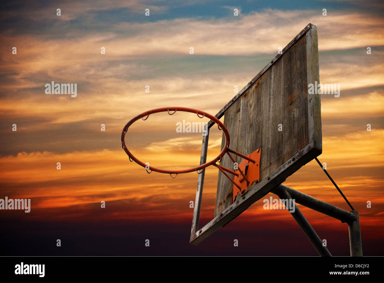 Street basketball. Old basketball hoop and a back board in sunset against the dark orange sky. Stock Photo