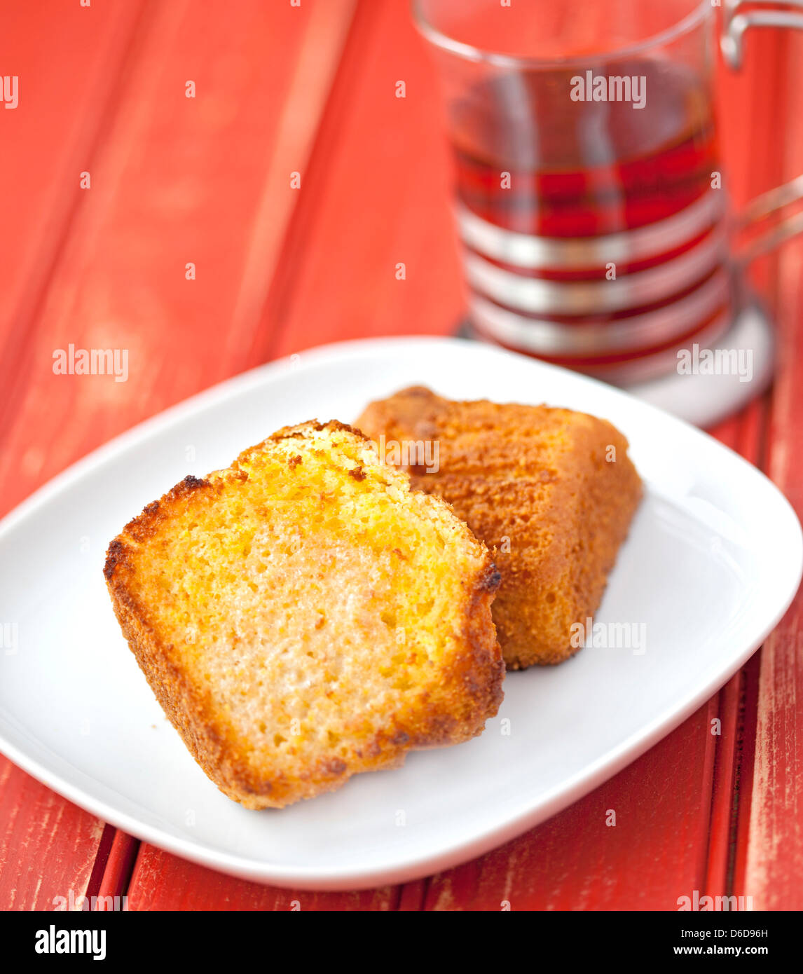 Toasted corn muffin with butter and a cup of tea on a wooden table Stock Photo
