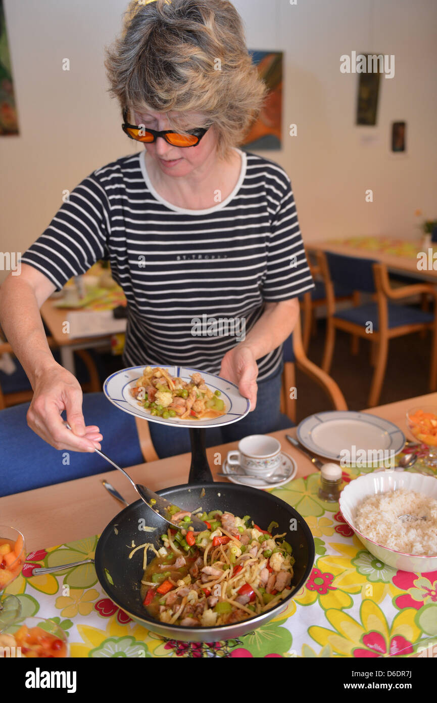 Ilse Schmidt, who is visually impaired, serves a plate of food during a