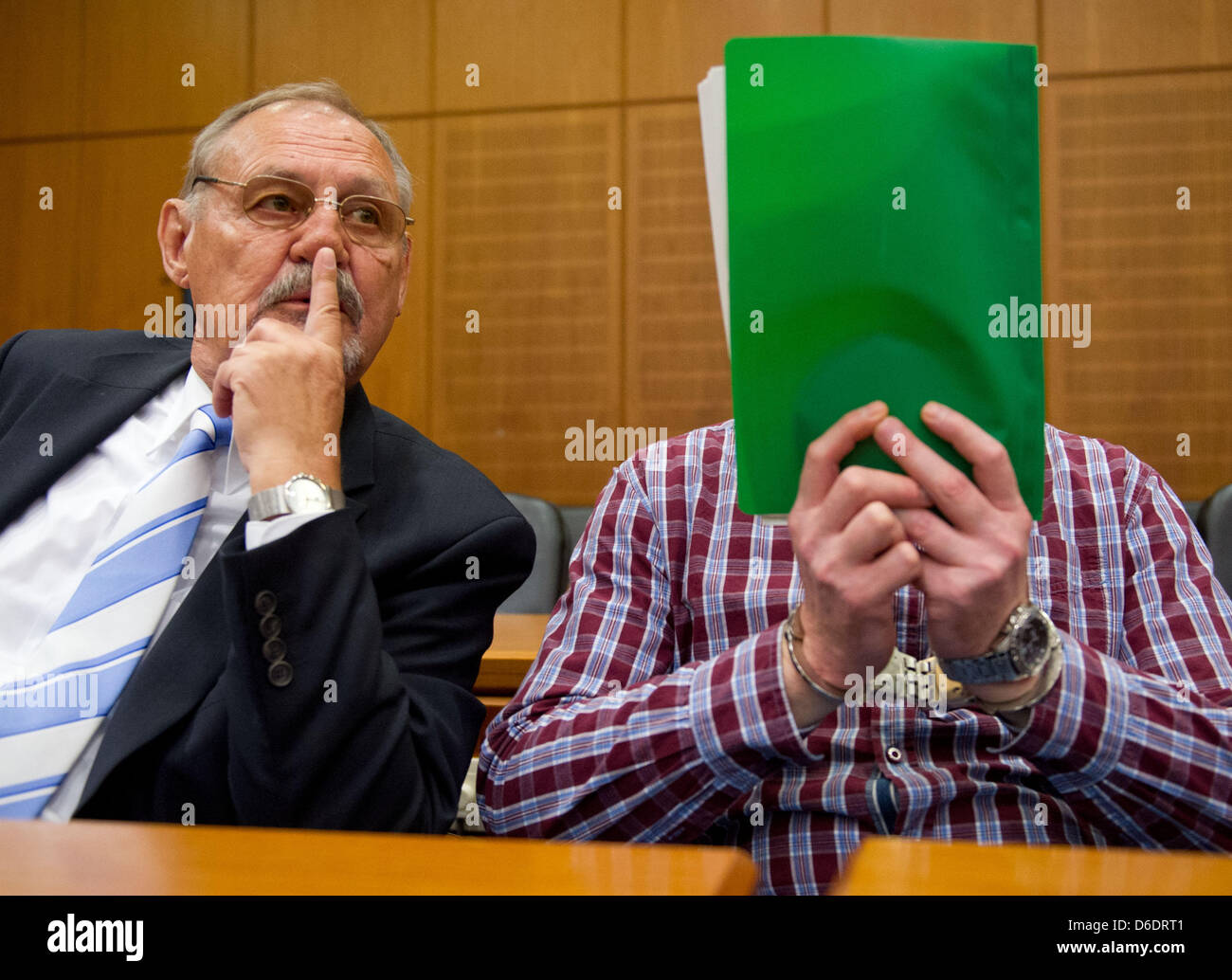 Bus hijacker Thomas Feldmann hides his face behind files at the start of his trial in a high-security court room of the district court in frankfurt Main, Germany, 12 September 2012. His lawywe Hans-Juergen Borowsky sits next to him. 47 year old Feldmann is accused of extortion, deprivation of liberty and assualt, amongst other things. Thomas Feldhofer was the most wanted criminals  Stock Photo