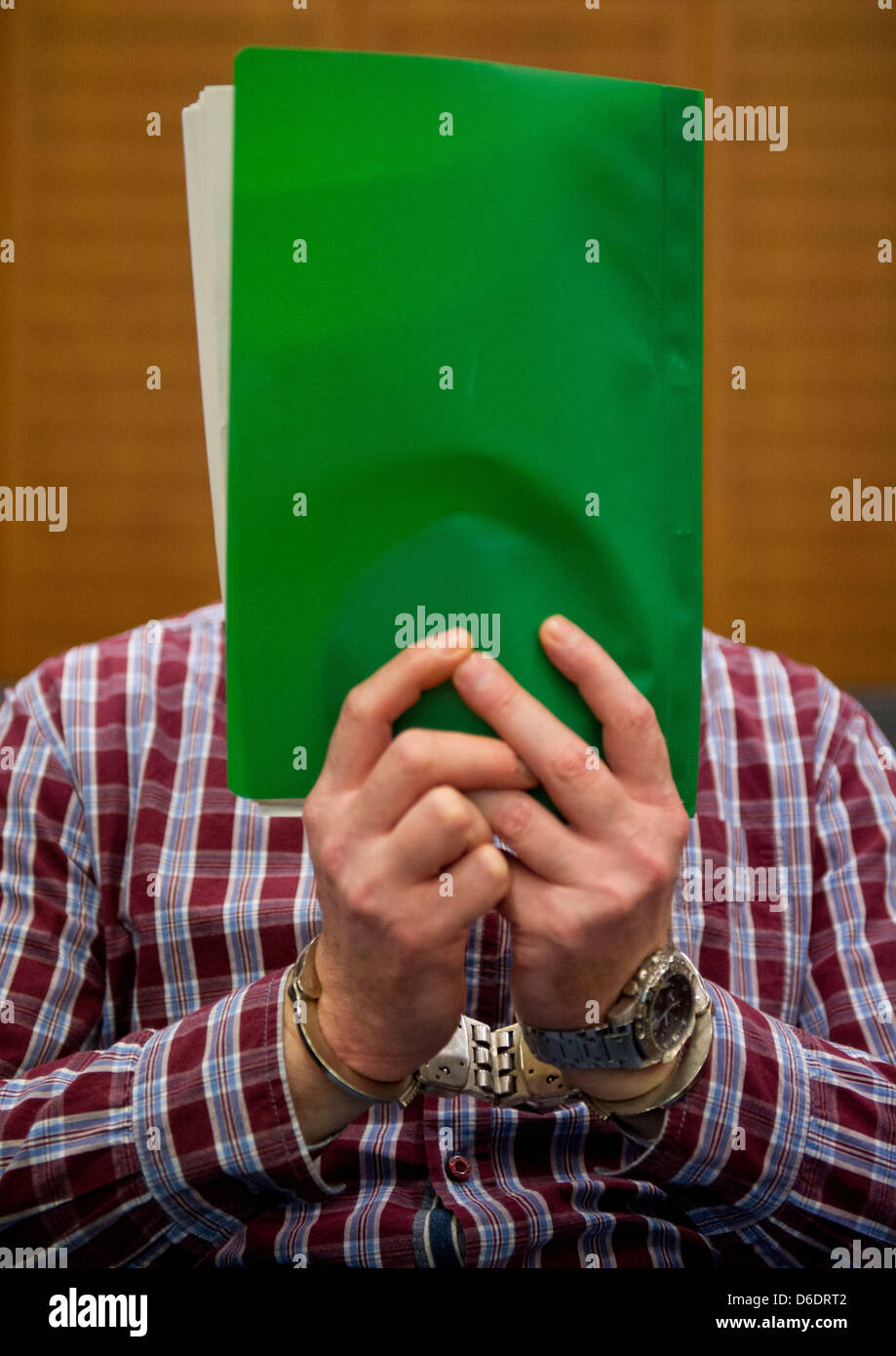 Bus hijacker Thomas Feldmann hides his face behind files at the start of his trial in a high-security court room of the district court in frankfurt Main, Germany, 12 September 2012. The 47 year old is accused of extortion, deprivation of liberty and assualt, amongst other things. Thomas Feldhofer was the most wanted criminals in Germany for some months. He is accused of 19 crimes i Stock Photo