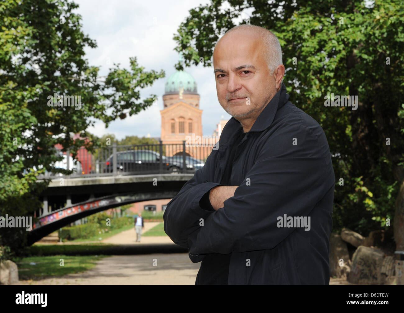 dpa-Exclusive: The artist and architect Yadegar Asisi stands on the bridge on Waldemarstraße with the Sankt-Michael-Kirche (church of saint michael) in the background near the Engelbecken in the Kreuzberg neighbourhood in Berlin, Germany, 12 September 2012. The view of the church was blocked by the Berlin Wall, which used to run along the square and in 1986 Asisi painted a fictiona Stock Photo