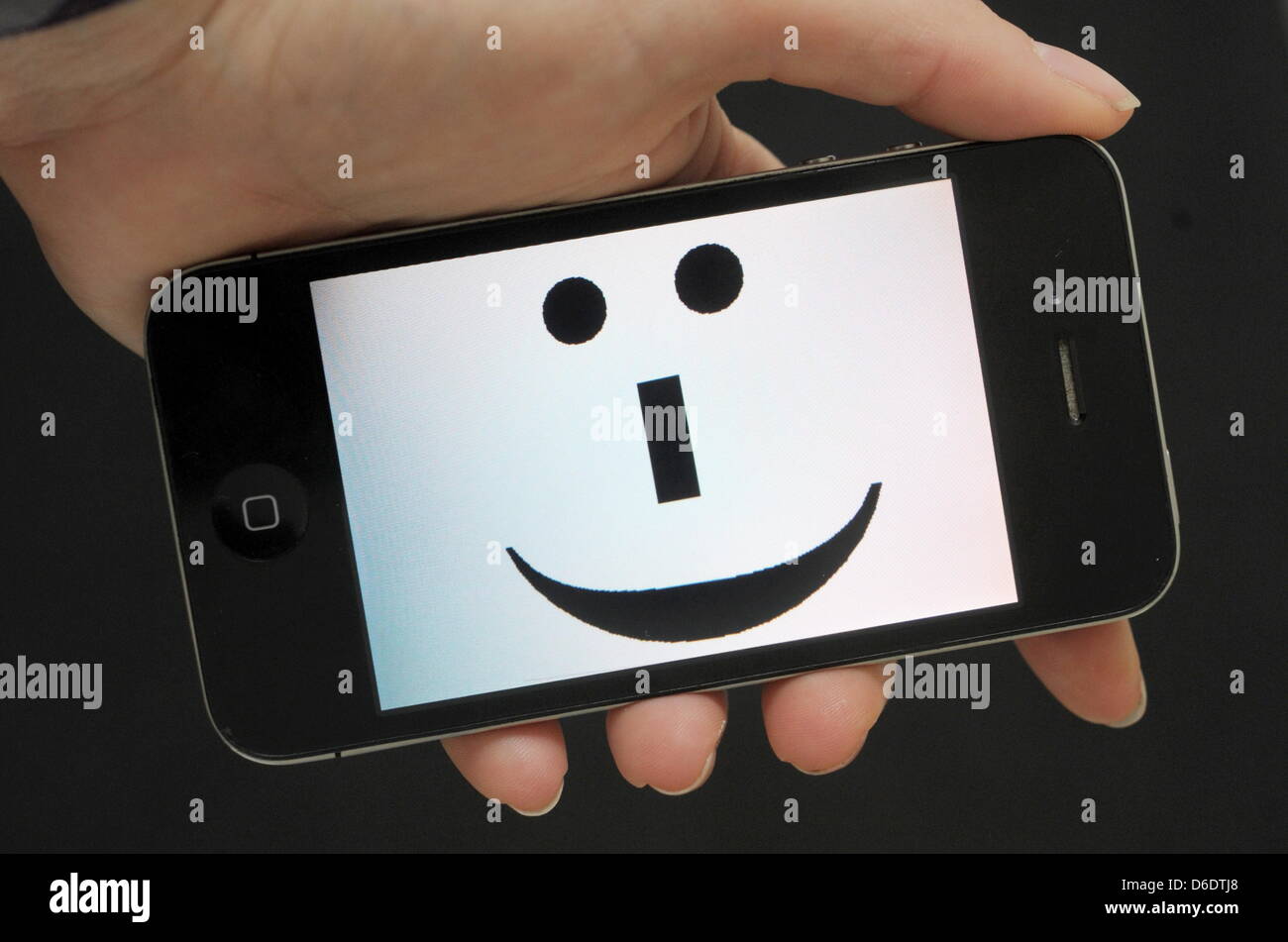 The illustration shows a smartphone with a smiley on display in Stuttgart, Germany, 12 September 2012. The worldwide known digital smiley symbole is celebrating its 30th anniversary on 19 September 2012. Smily symbole have become a common part in the culture of typewriting, i.e. in emails, chats and instant text messages. Photo: Franziska Kraufmann Stock Photo