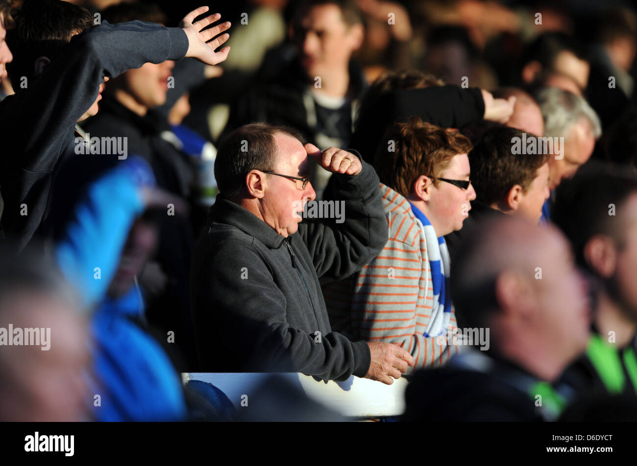 Football fans shiled their eyes from bright sunlight standing in