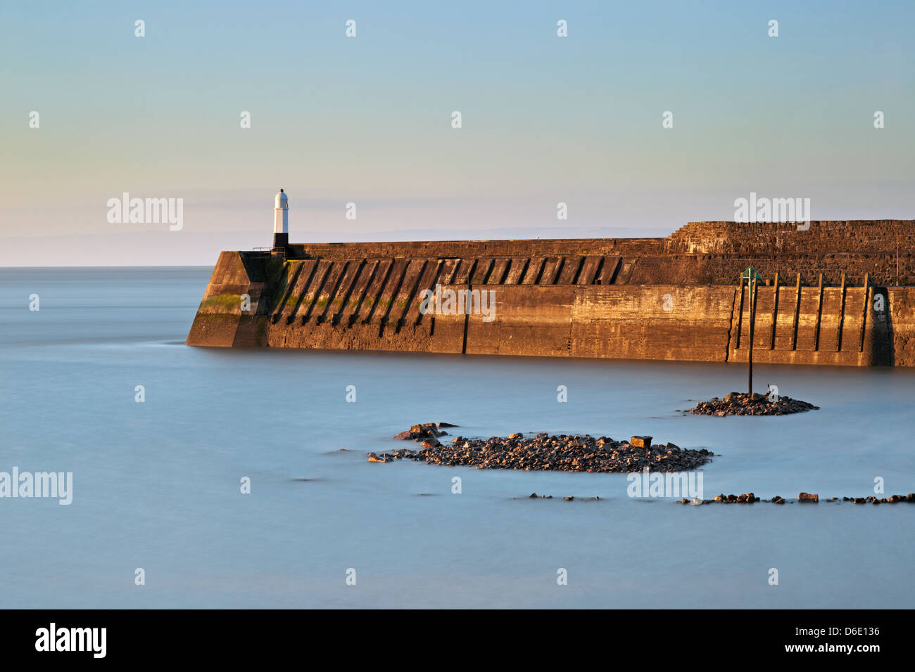Long exposure photograph of Porthcawl lighthouse and harbour wall taken at sunrise. Stock Photo