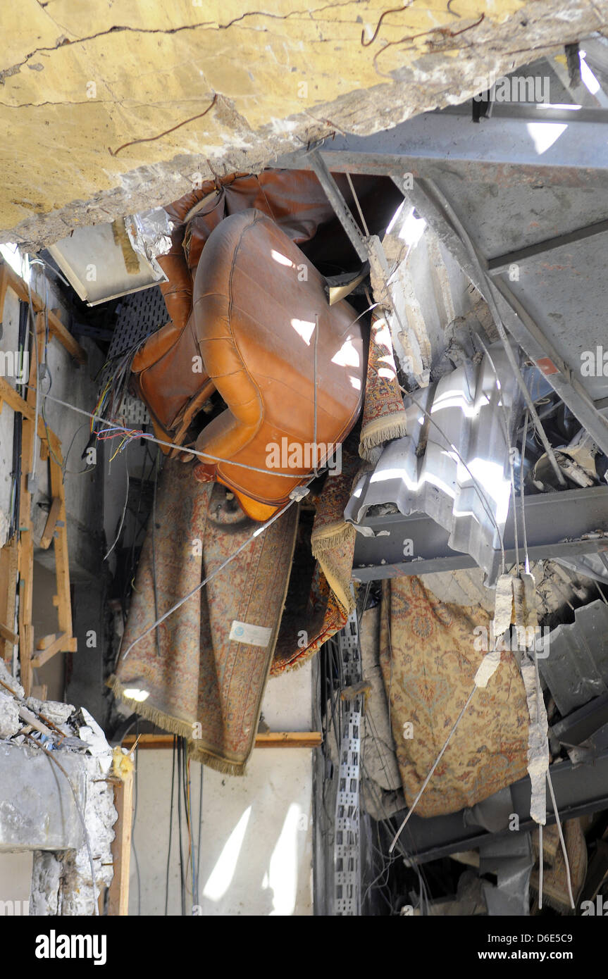 An armchair and a carpet hang through a hole in the ceiling of a destroyed office building in the Bab al-Azizia district of Tripoli, Libya, 1 December 2011. The district of Bab al-Azizia was one of the targets of intensified NATO bombing campaigns starting from the end of March 2011 during the Libyan civil war. The area accmmodated various government palaces, adminstration offices  Stock Photo