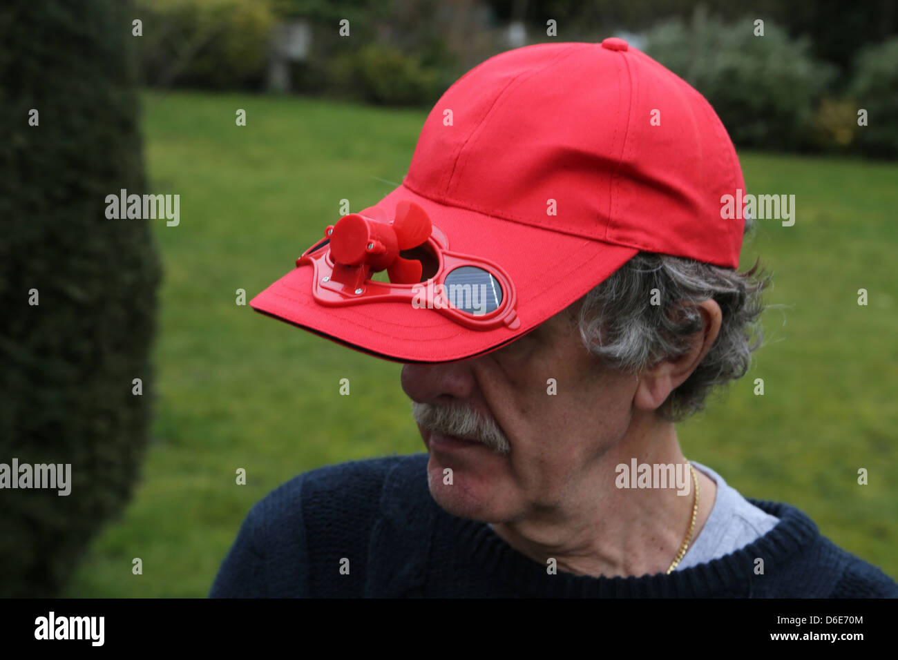 Man Wearing Red Baseball Cap With Solar Powered Fan Stock Photo