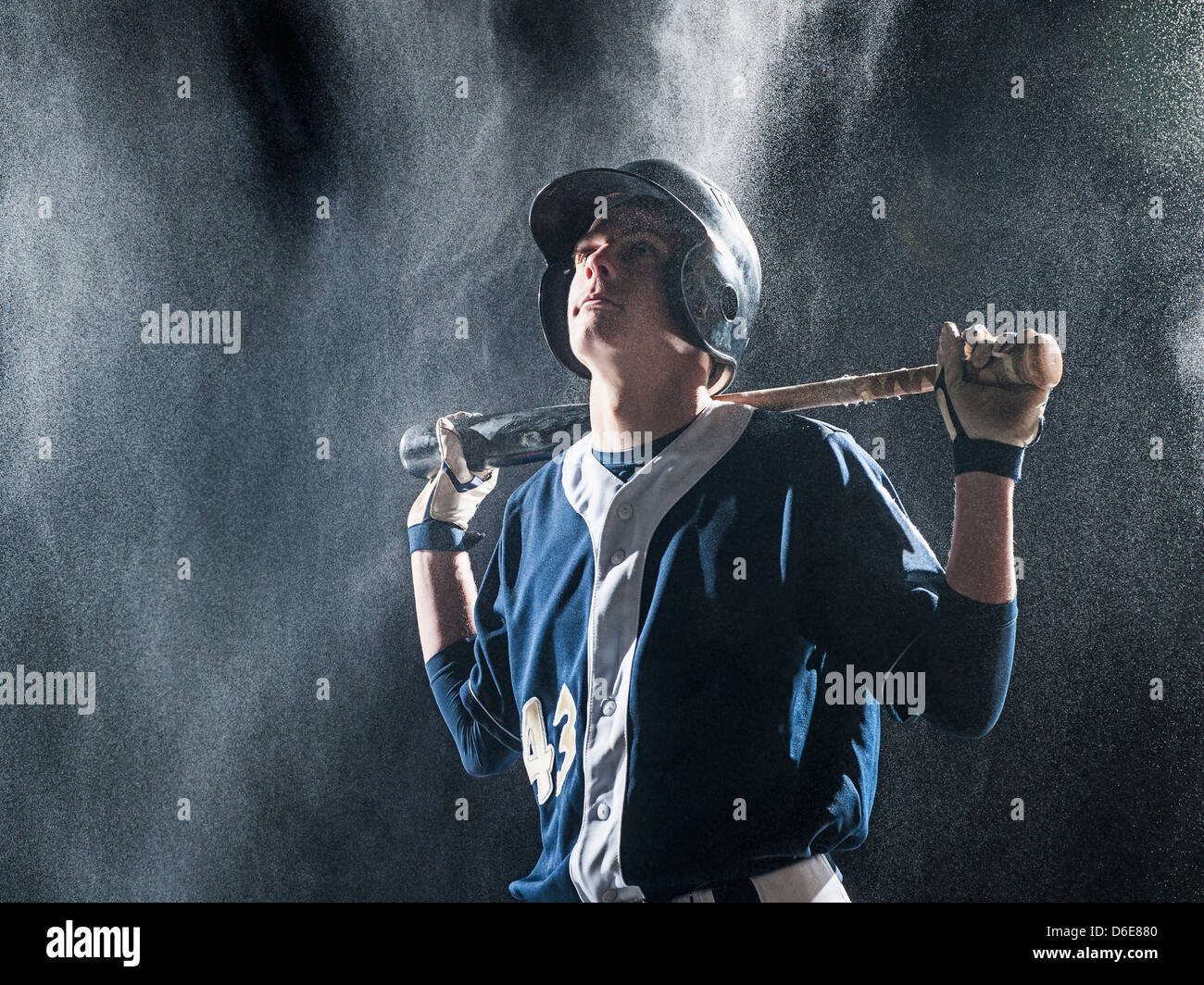 Caucasian baseball player standing in rain Stock Photo
