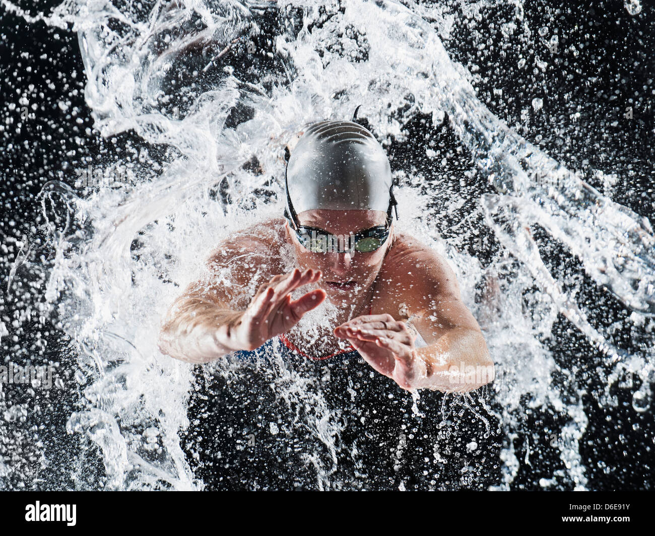 Caucasian swimmer splashing in water Stock Photo