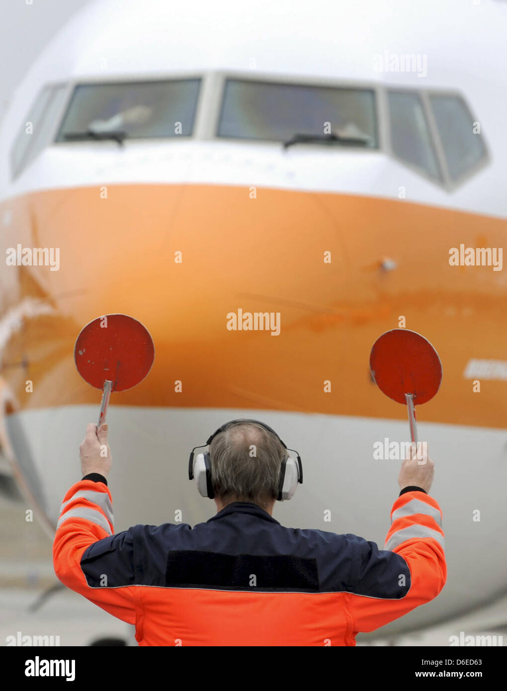 (dpa-file) - A file picture dated 27 January 2009 shows an employee of the airport in Hamburg directing a Boeing B 737-800 to its parking position, Germany. New billion euro contracts for Boeing and Airbus: the budget airline Norwegian has ordered 222 airplanes from the US and European producers. According to reports of Norwegian on 25 January 2012, Boeing shall deliver 100 airplan Stock Photo