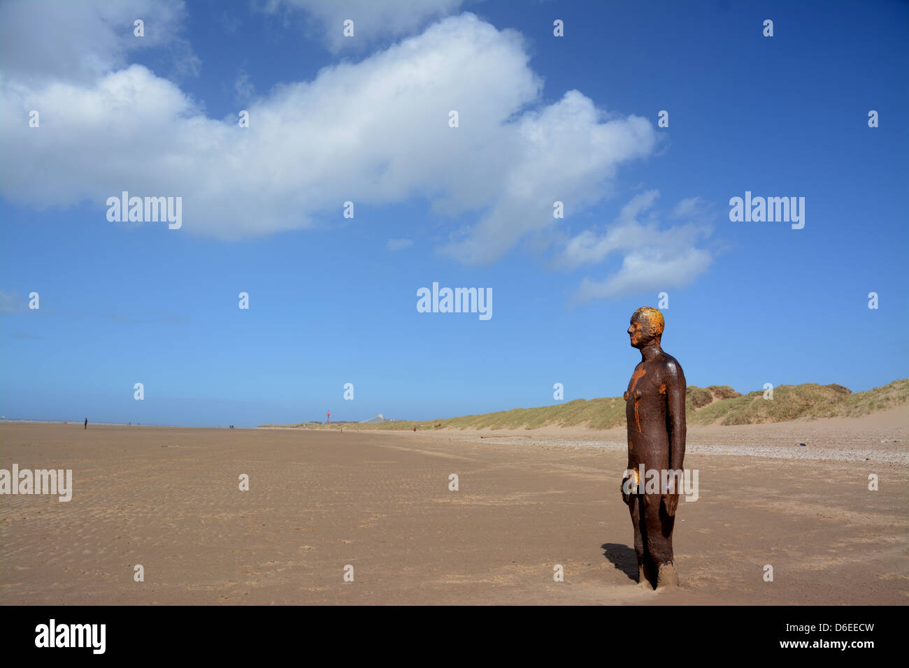 Antony Gormley's Another Place statues on the beach at Crosby with blue