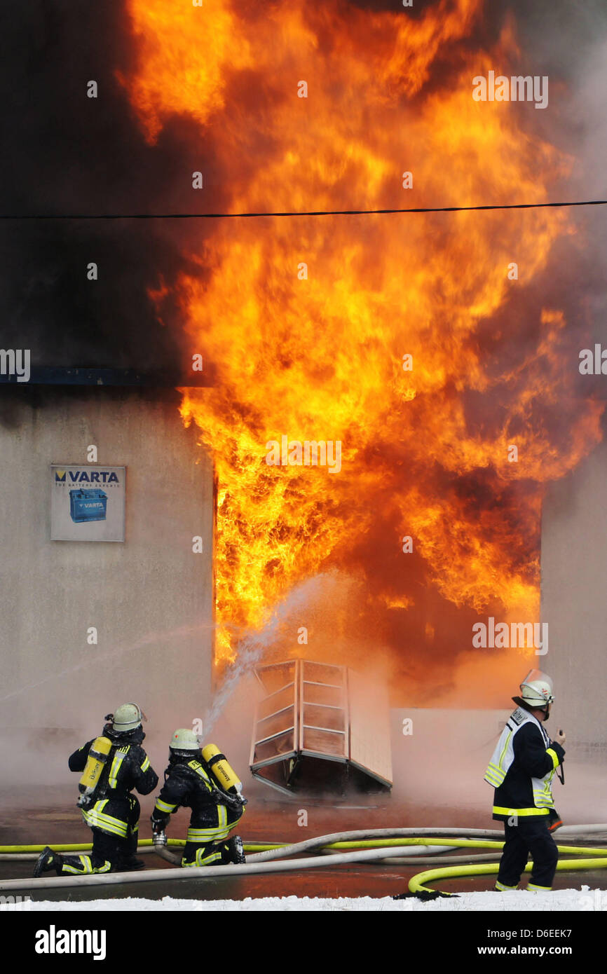 Fire fighters try to extinguish a fire in an oil and chemical warehouse in Bad Laasphe, Germany, 28 January 2012. Despite the fire fighting operation the warehouse burnt out completely.  Numerous barrels of chedmicals has exploded. Due to the Zahlreiche Fässer mit Chemikalien explodierten. Because of the strong smoke production police asked the neighbours to keep doors and windows  Stock Photo