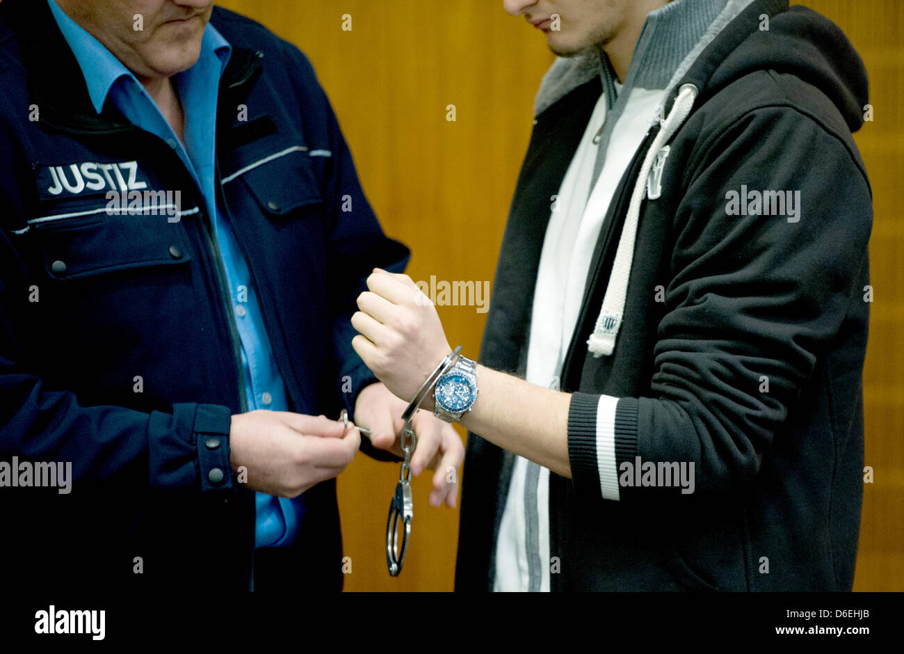 A judicial officer takes off the handcuffs of defendant Arid Uka (R) at the regional appeal court in Frankfurt Main, Germany, 02 February 2012. Uka is on trial for murder in two cases and attempted murder in further three. On 02 March 2011, he shot two US soldiers at the airport and injured two other soldiers severely in an assasination attempt. Photo: Arne Dedert Stock Photo