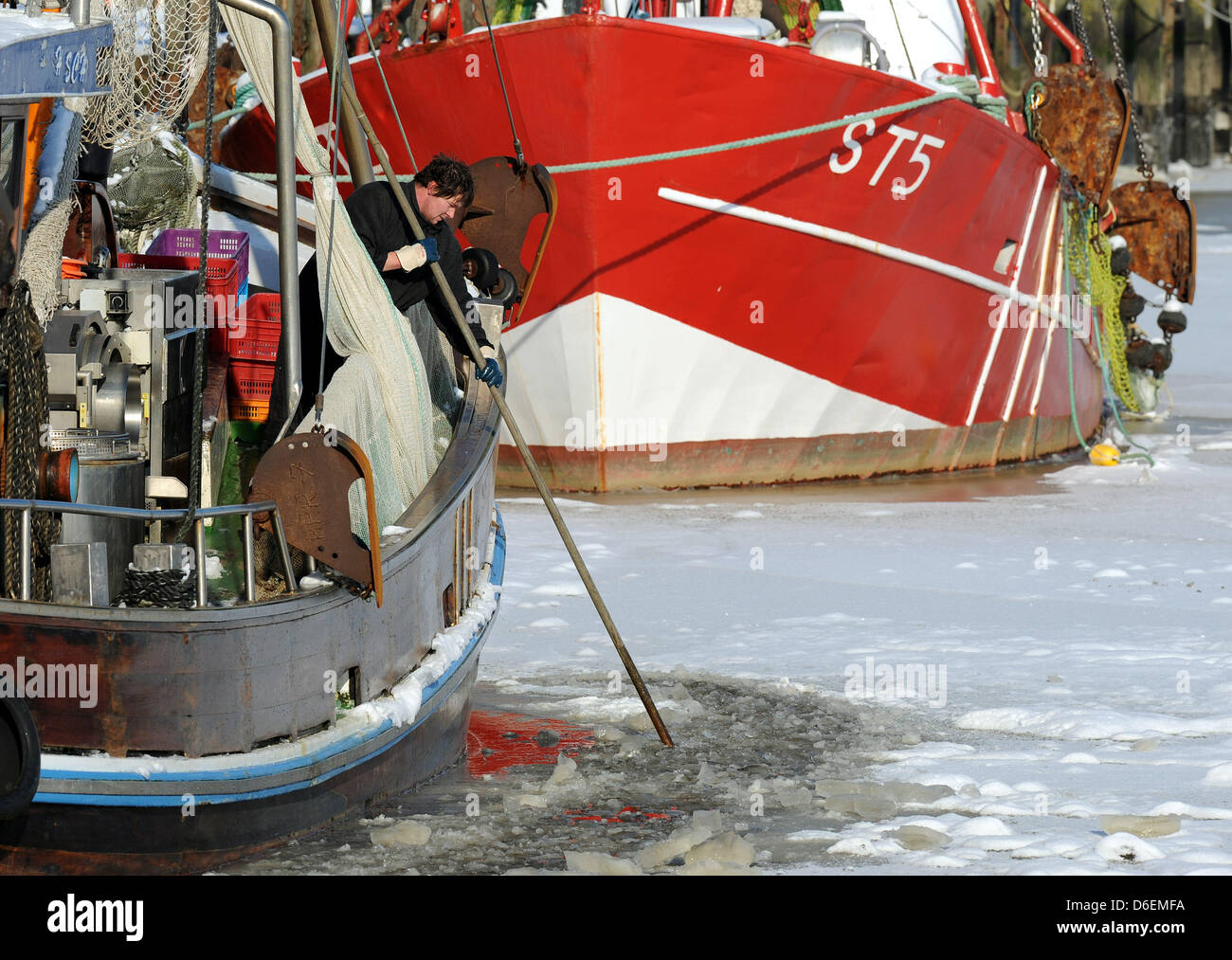 Fishers of the crab cutter HAR7 frees the wooden body of his vessel from ice in the port of Harlesiel, Germany, 05 February 2012. The weather is frosty in Germany and currently affects the waterway transport. Photo: INGO WAGNER Stock Photo