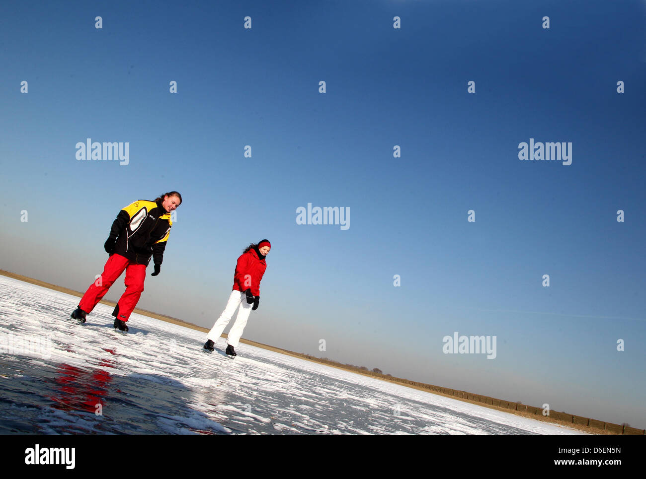 Michelle (l) und Jana gleiten am Montag (06.02.2012) auf dem zugefrorenen Altrhein bei Xanten über das Eis. Die starken Minustemperaturen in den letzten Tagen haben die Wasserlandschaft in eine Eisfläche verwandelt.  Foto: Roland Weihrauch dpa/lnw  zu KORR:' Stock Photo
