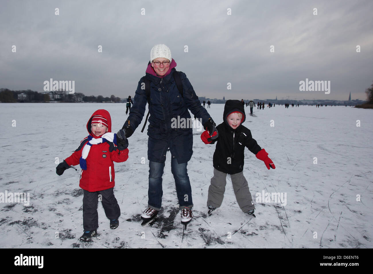 Alke Fingerhut (C) and her children Hannes (L-R) and Mars walk on the frozen Outer Alster in Hamburg, Germany, 07 February 2012. The frozen Outer Alster could be used at one's own risk since yesterday. In some places the ice is 18 cm thick. Photo: MALTE CHRISTIANS Stock Photo