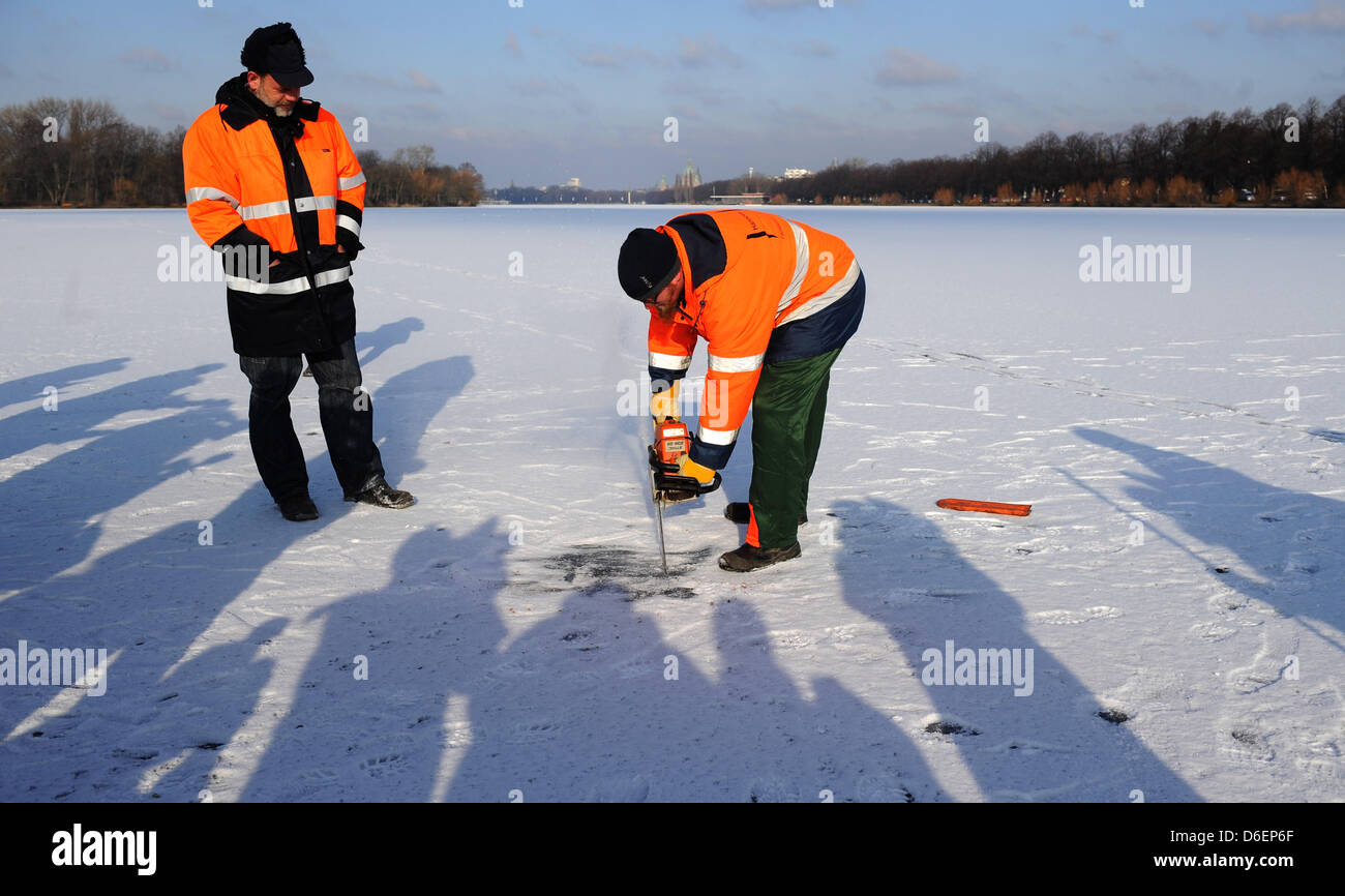 Two building authority employees measure the thickness of the ice on the Maschsee in Hanover, Germany, 08 February 2012. After it was closed for days, the Maschsee may be used for skating or for walking on from today. The city has measured an ice blanket of at least 13 cm in thickness. Photo: JULIAN STRATENSCHULTE Stock Photo