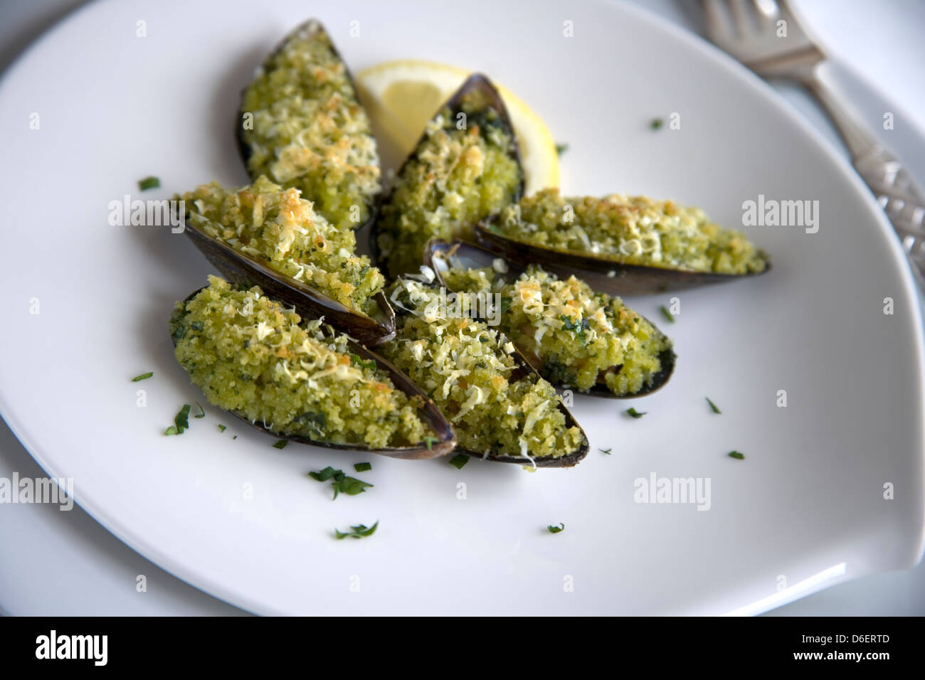 Plated mussels in half-shell with Provencale crumb/ step shot Stock Photo