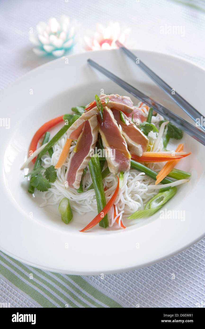 Seared Tuna steaks on rice noodles with shredded vegetables and Thai