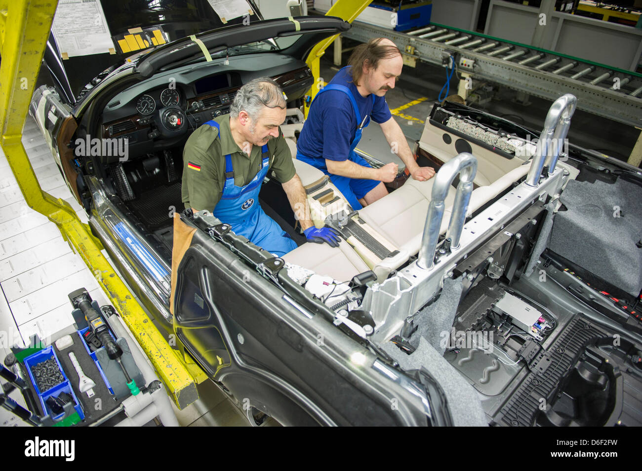 Several employees of car manufacturer BMW work on a car at the BMW factory in Regensburg, Germany, 10 April 2013. Photo: Marc Mueller Stock Photo