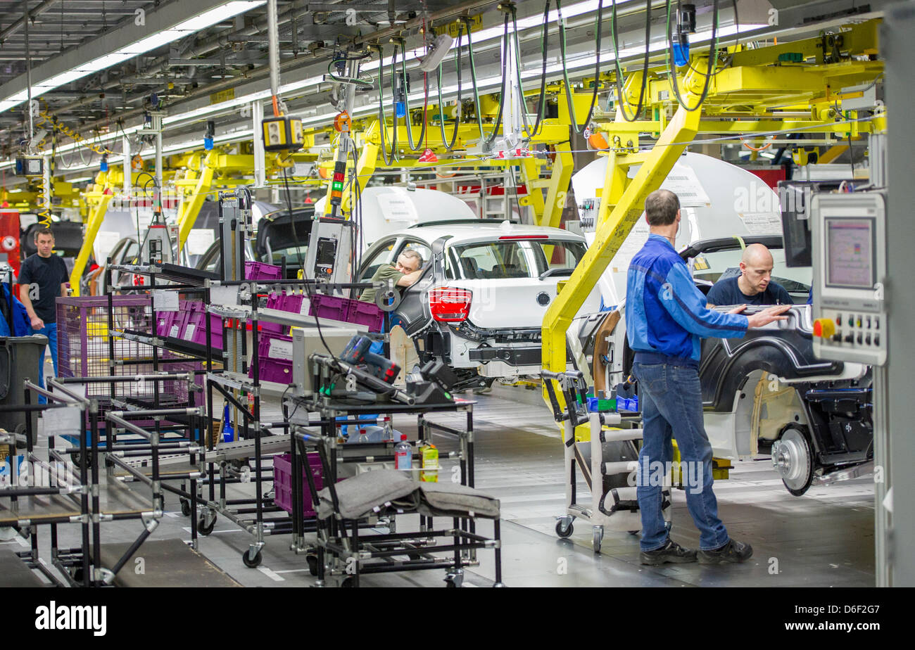 Several employees of car manufacturer BMW work on a car at the BMW factory in Regensburg, Germany, 10 April 2013. Photo: Marc Mueller Stock Photo