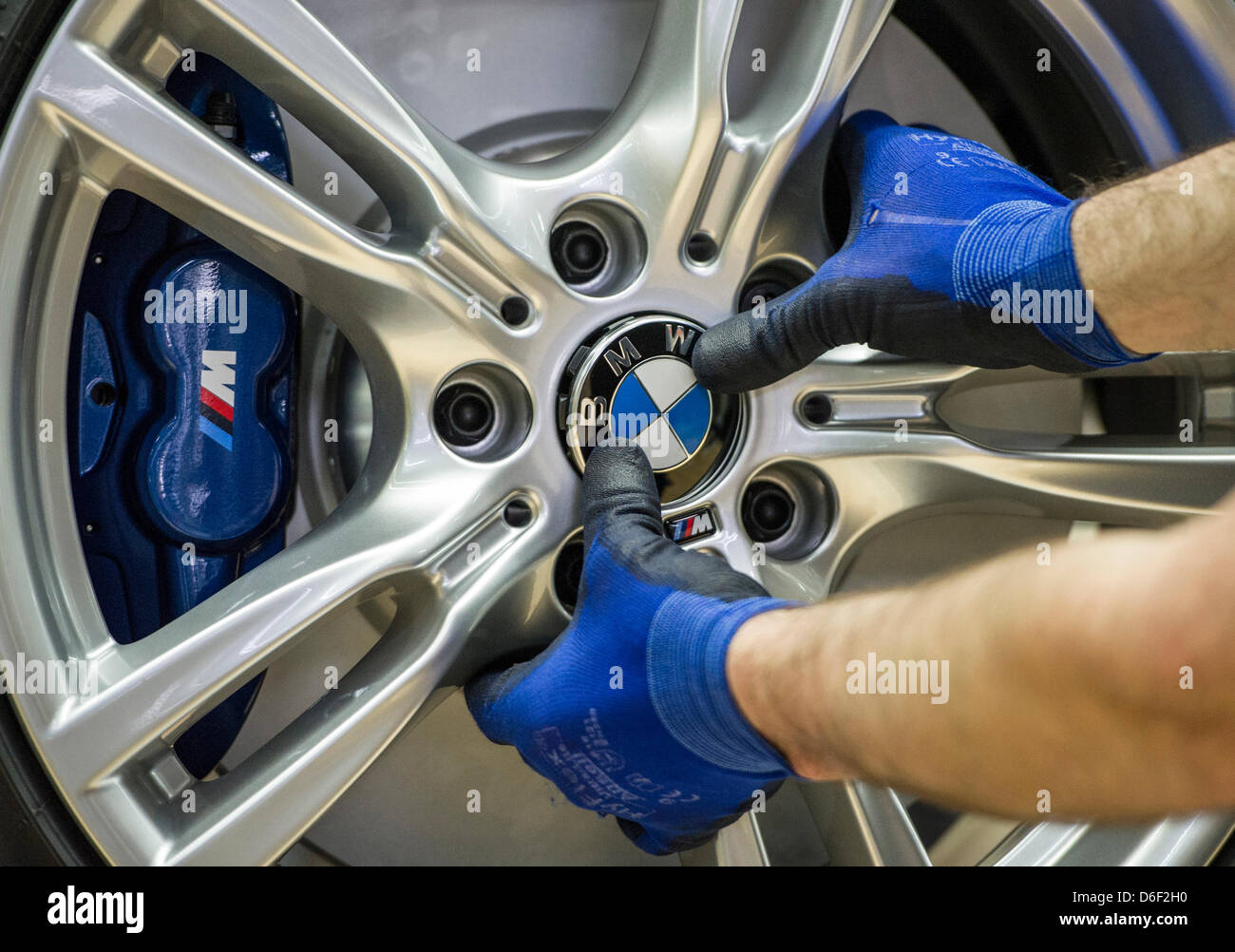 An employee of car manufacturer BMW works on a car at the BMW factory in Regensburg, Germany, 10 April 2013. Photo: Marc Mueller Stock Photo