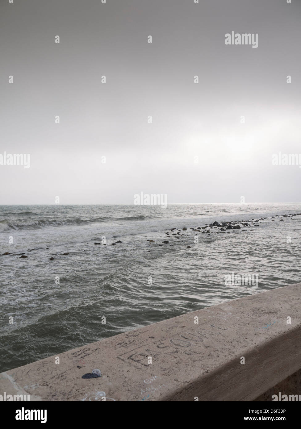 balustrade on rough sea in the winter with the cloudy sky. Stock Photo