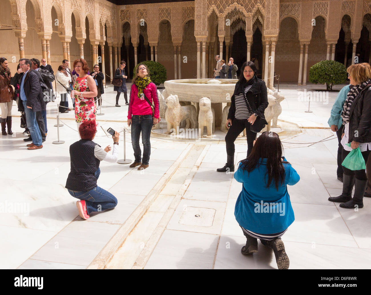 Tourists posing in Patio of the Lions, Patio de los Leones, Nasrid Palaces, Alhambra, Granada Stock Photo