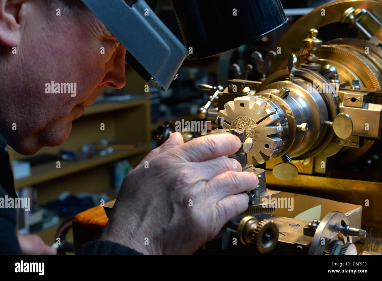 Jeweler engraving a piece of jewelry on an antique rose engine lathe