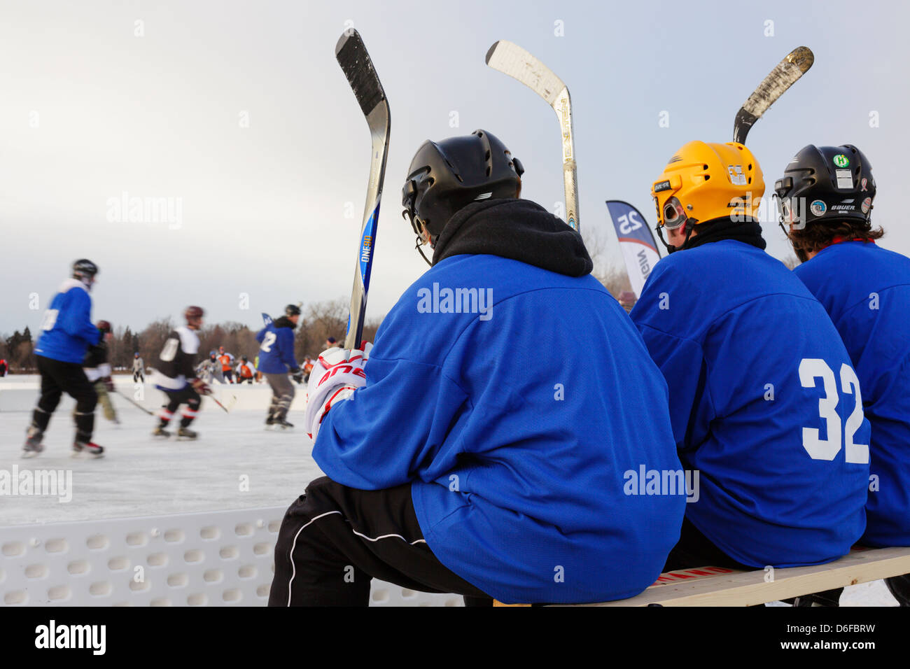 Players watch the action from the team bench during a game at the U.S. Pond Hockey Championships on Lake Nokomis. Stock Photo