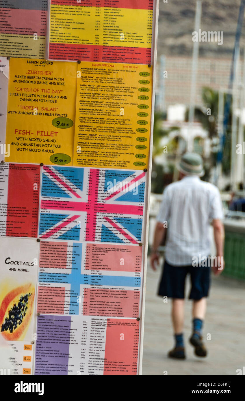 BRITS ABROAD UNION JACK FLAG RESTAURANT  Multilingual menu board with national flags to attract tourists with stereotypical British tourist behind Stock Photo