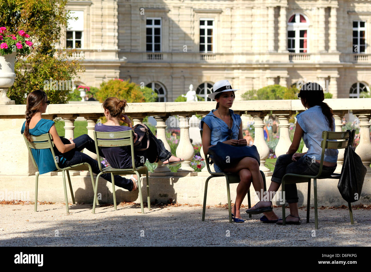 Summer in Paris. Girls chatting sitting in famous Luxembourg garden chairs in front of the Senat Palace, Paris, France Stock Photo