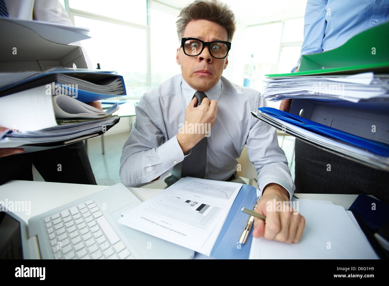 Shocked accountant looking at camera surrounded by huge piles of ...