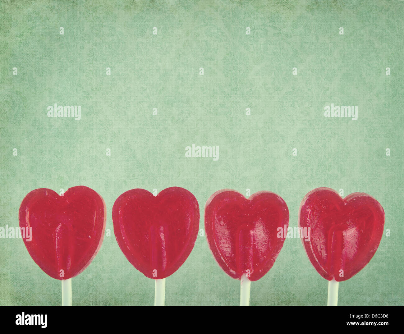 Row of red lollipop hearts on green vintage background with copy space