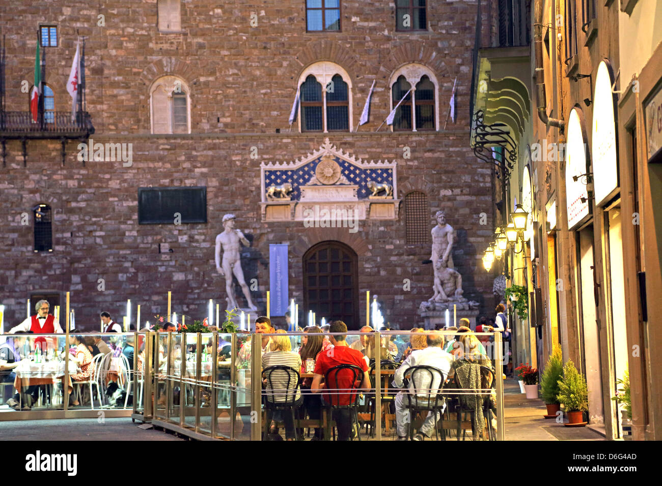 Restaurants at night in Piazza della Signoria Florence Italy. Palazzo Vecchio and a replica statue of David in the background. Stock Photo