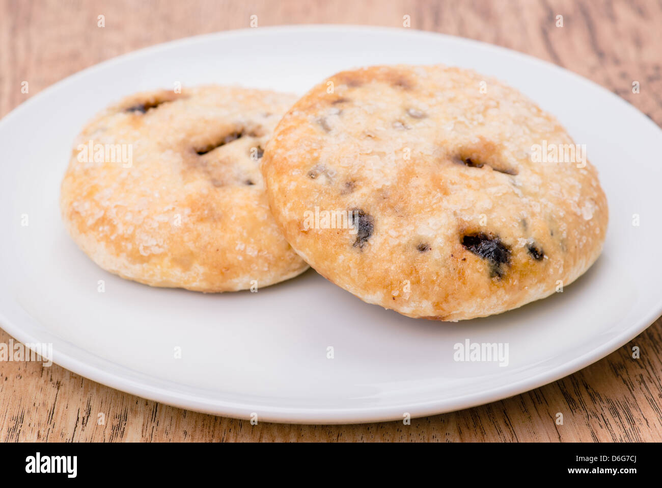 Two Eccles cakes on a white plate, shallow depth of field. An Eccles cake is a variety of cake from the north of England, UK. Stock Photo