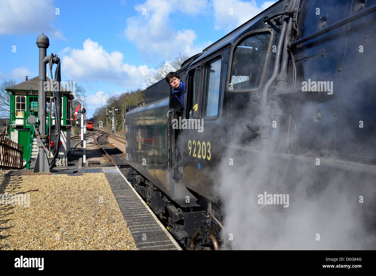 North Norfolk Railway steam train (Riddles 9F class loco) at Holt Station, Norfolk, England with fireman looking out of cab. Stock Photo