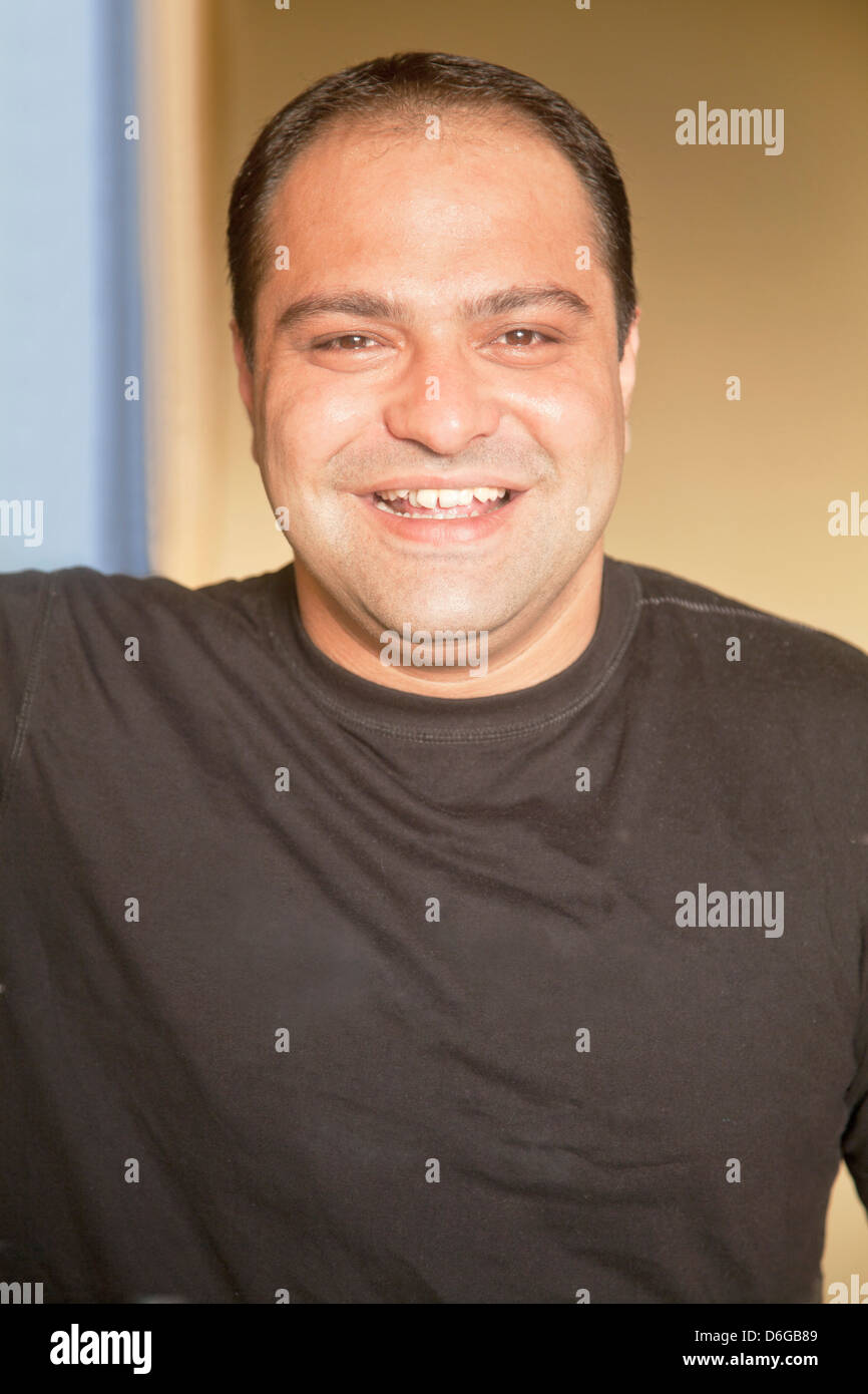 Vertical close up of a smiling happy asian young man with plain black T shirt, well groomed, receding hairline Stock Photo