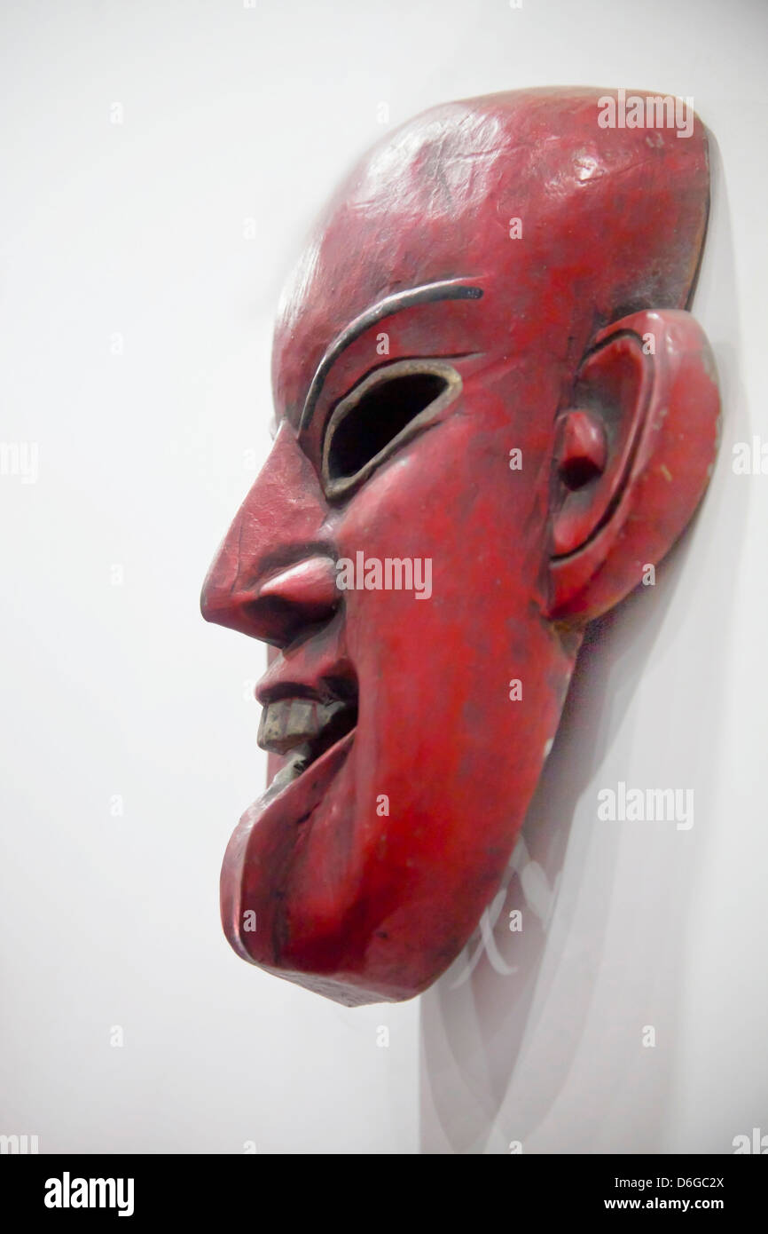 Vertical take of a generic mounted hand carved smiling mask. SHot location India Stock Photo