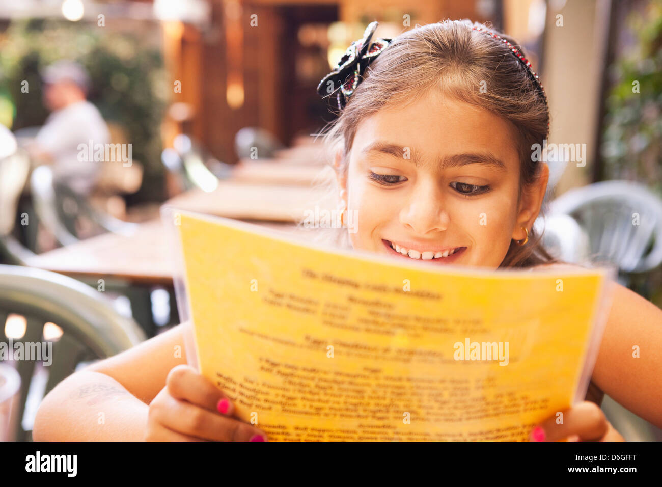 Mixed race girl reading menu in restaurant Stock Photo