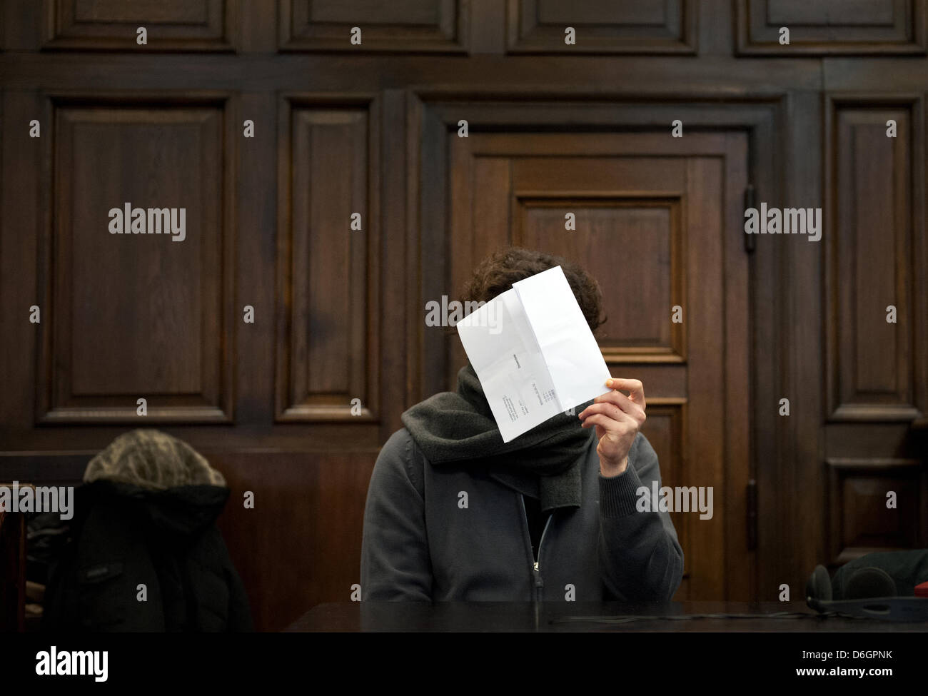 The 27 year old accused holds a piece of paper in front of his face at the District Court in Hamburg, Germany, 22 February 2012. The psychologically ill man is on trial for the murder of a younf US American woman in a Hamburg hotel. Photo: CHRISTIAN CHARISIUS Stock Photo