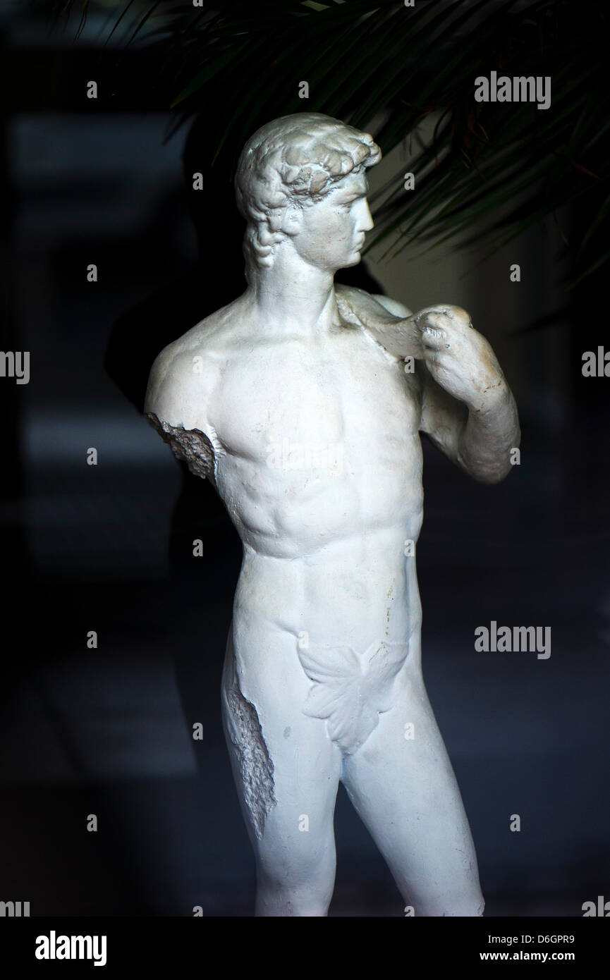 A male statue missing an arm is pictured in front of a Greek restaurant